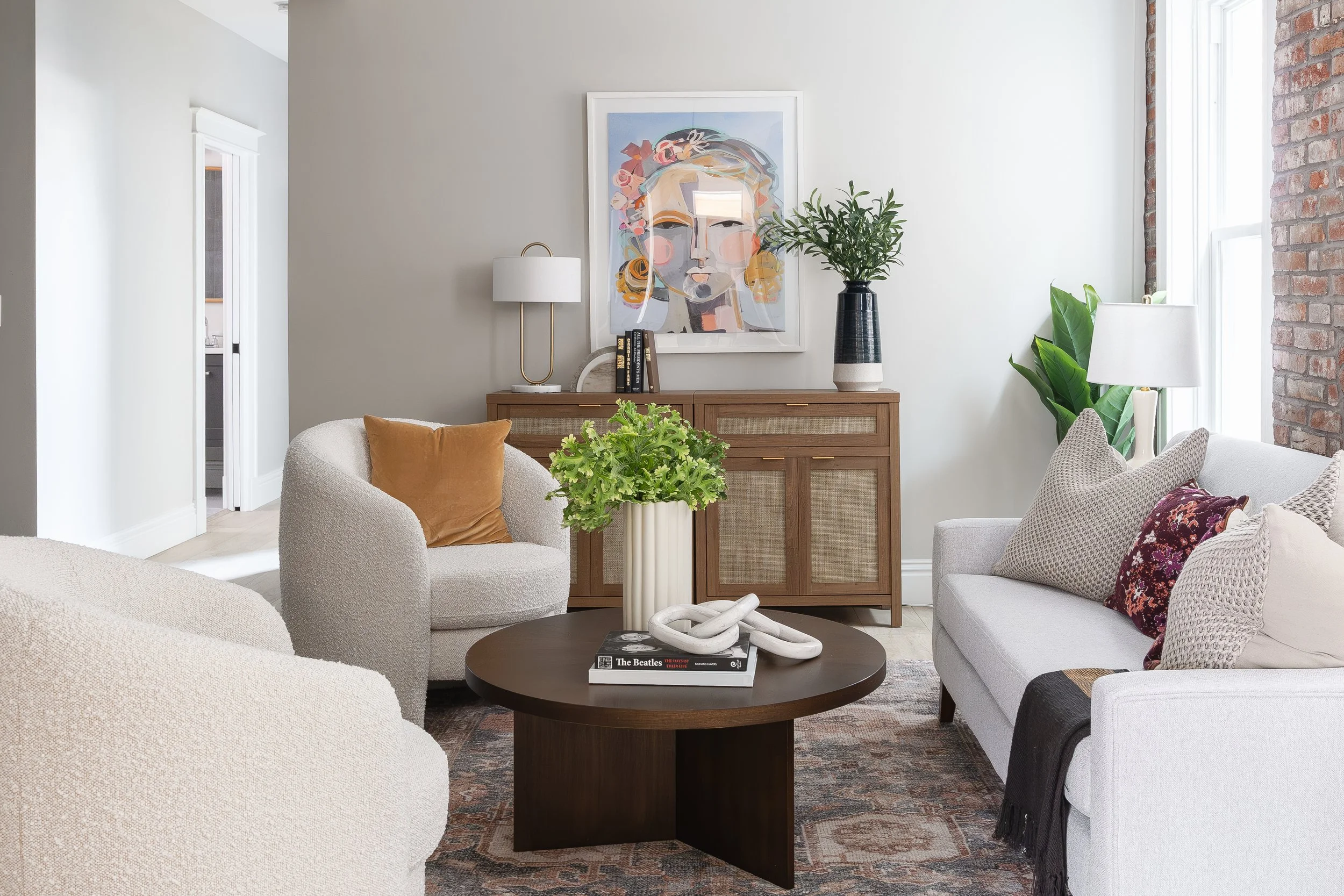 A bright living room with lush greenery adding natural warmth and vibrancy to the neutral decor.